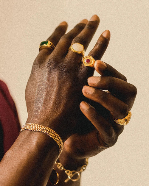 Closeup of man's hands wearing multiple MAPLE rings & bracelets and adjusting ring