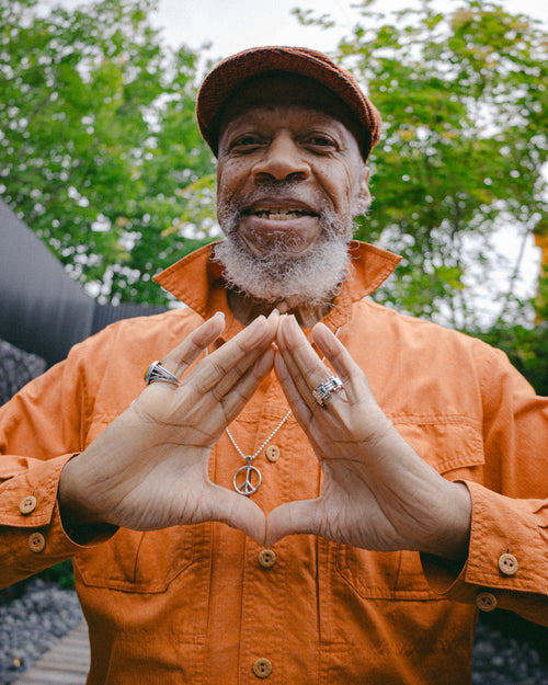 Laraaji throwing up a diamond hand gesture wearing MAPLE jewelry