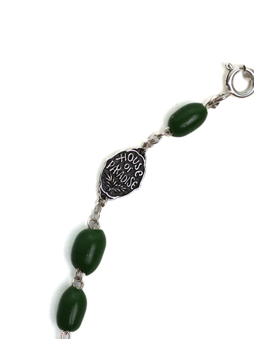 Bracelet with green beads and silver medallion on a white background