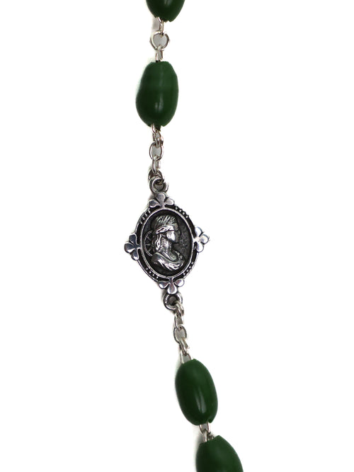 Necklace with green beads and a silver medallion on a white background