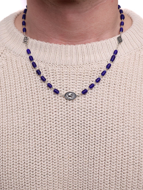 Necklace with blue beads and silver medallions on a beige sweater