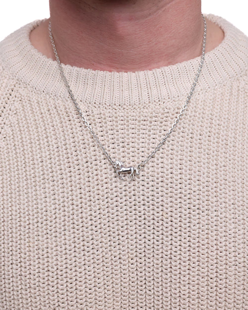 Necklace with a small horse pendant on a person wearing a light beige sweater.