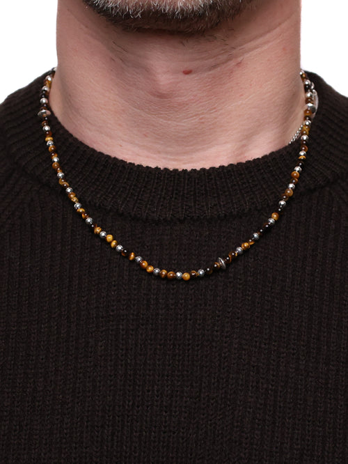 Close-up of a beaded necklace worn by a person against a black background