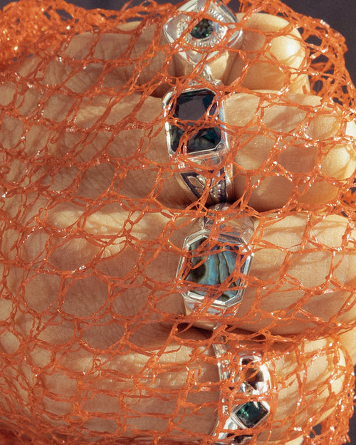 4 fingers wearing MAPLE jewelry covered in plastic orange netting