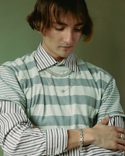 Man in striped shirt on green background wearing MAPLE jewelry