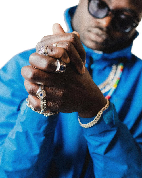 Unfocussed man with clasp hands in focus wearing MAPLE Silver 925 rings and bracelets