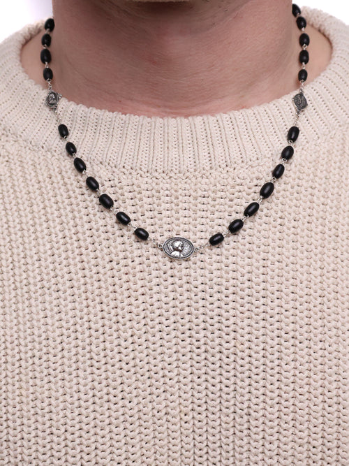 Necklace with black beads and silver clasp on a beige sweater