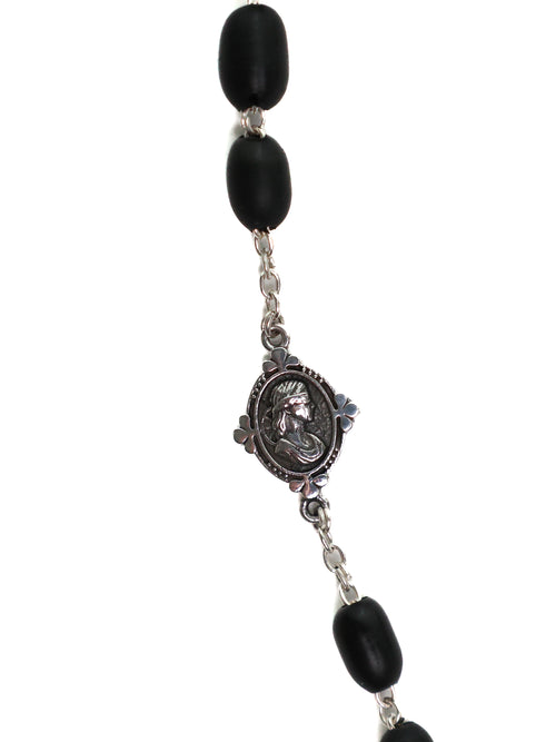 Black beaded rosary with a central silver medallion on a white background