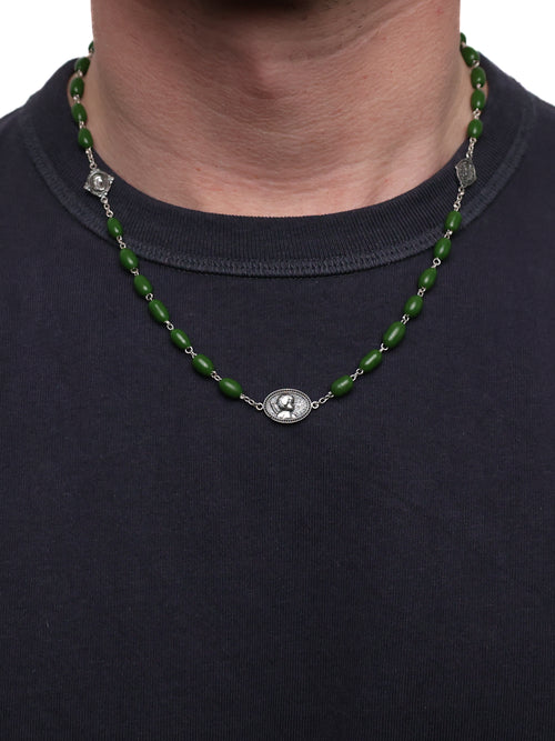 Green beaded necklace with silver medallions on a person wearing a dark blue shirt.