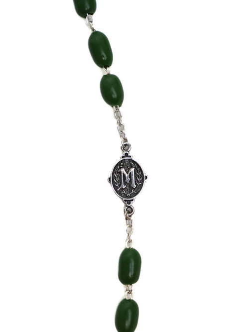 Necklace with green beads and a silver medallion on a white background