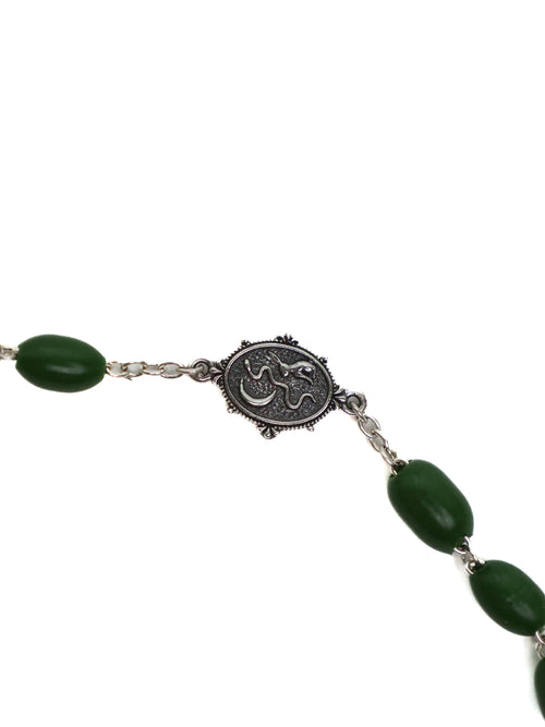 Necklace with green beads and a silver medallion on a white background