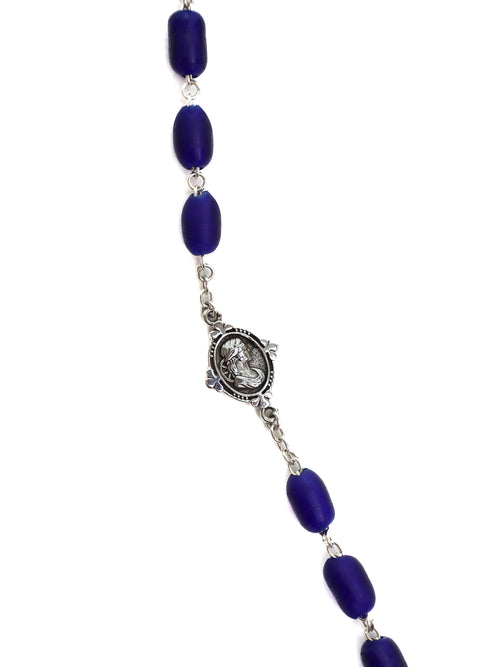 Necklace with blue beads and a silver medallions on a white background