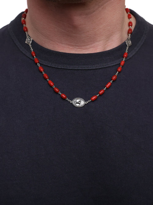 Red beaded necklace with silver medallions on a person wearing a black shirt