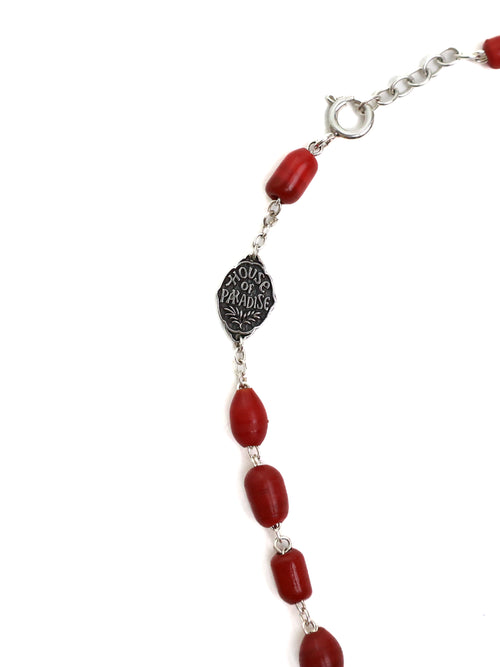 Bracelet with red beads and a silver medallion on a white background