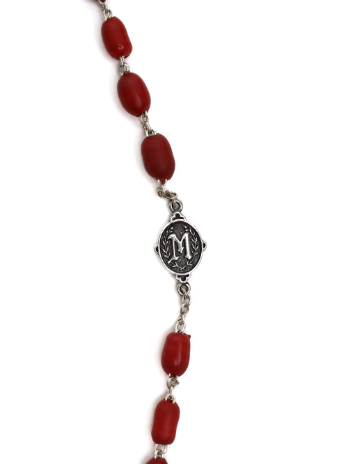 Necklace with red beads and a silver medallion on a white background