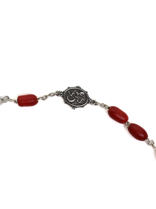 Bracelet with red beads and silver medallion on a white background