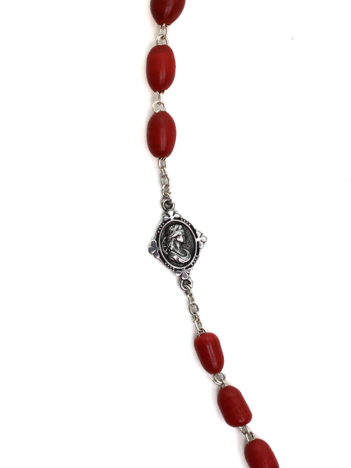 Necklace with red beads and a silver medallion on a white background