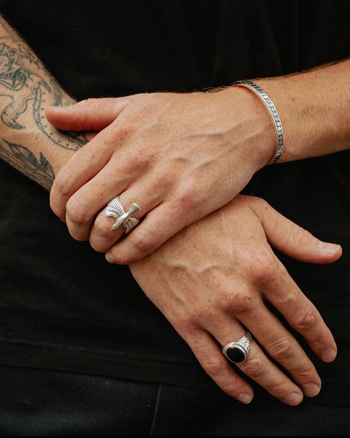 Left hand grabbing right hand wrist resting above waist wearing MAPLE Eagle Ring