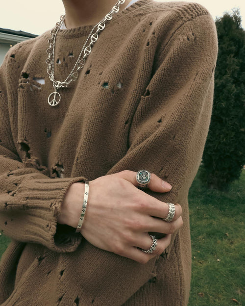 Young man in hole filled sweater grabbing elbow wearing MAPLE Weekend Champion Ring