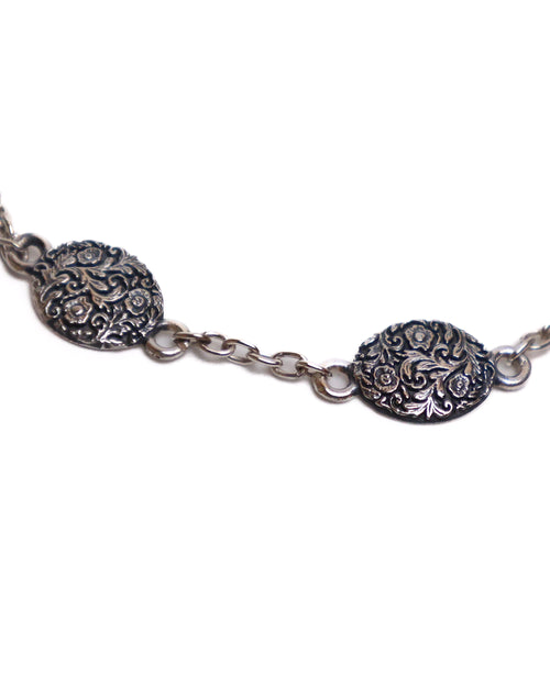 Silver bracelet with ornate medallions on a white background