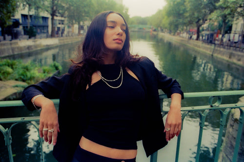 Anissa leaning on a bridge showcasing maple rings, bracelets & necklaces