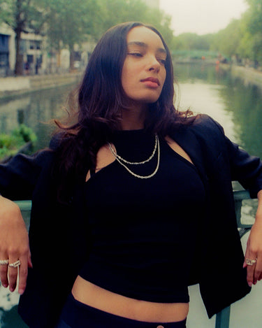 Anissa leaning on a bridge showcasing maple rings, bracelets & necklaces