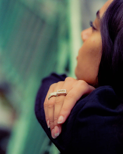 Anissa resting her arms and face on bridge railing with MAPLE rings in focus