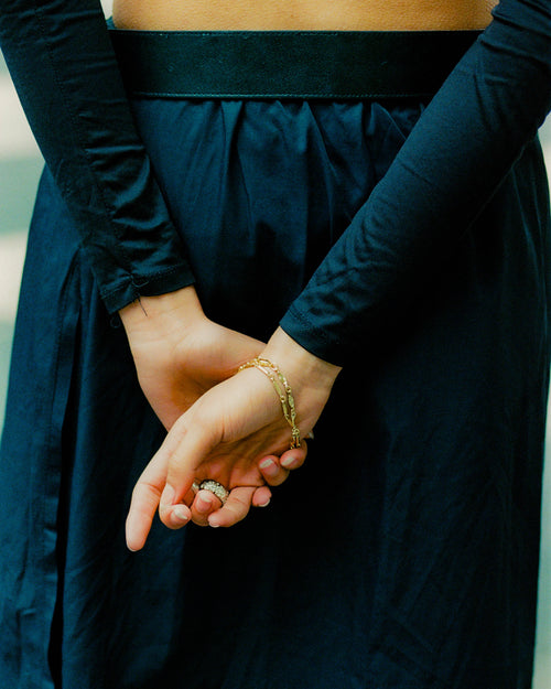 Close up of clasped hands behind woman's back pose wearing MAPLE bracelets & rings