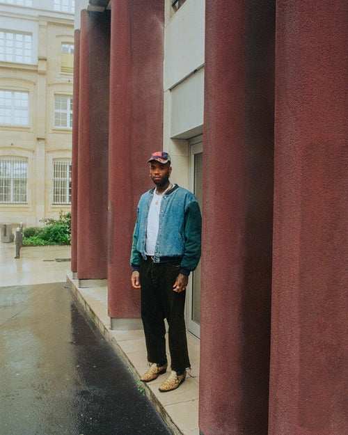 Artist Chino Creese in Paris France standing in front of a building with big red columns