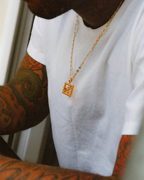 Artist Chino Creese wearing MAPLE Scorpio Necklace 14K Gold Zircon over a white t-shirt