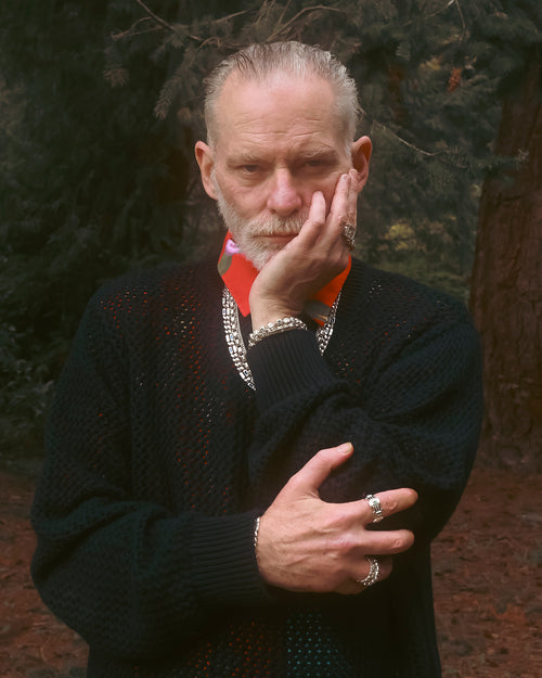 FW24 Editorial man standing in the forest with left hand under chin supported by the right hand wearing MAPLE jewelry